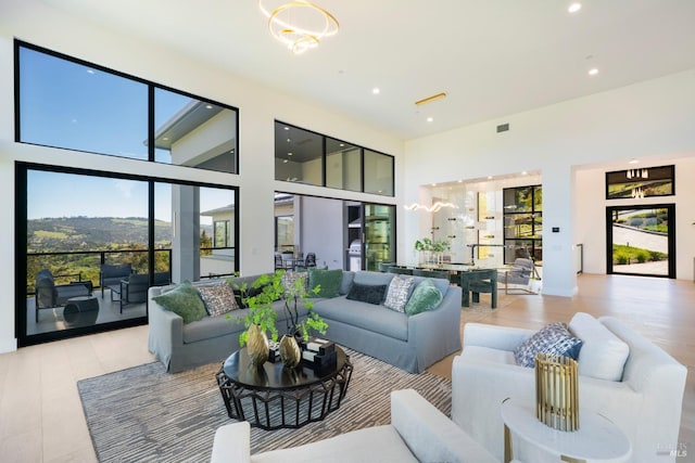 living room with recessed lighting, a chandelier, a towering ceiling, light wood finished floors, and visible vents
