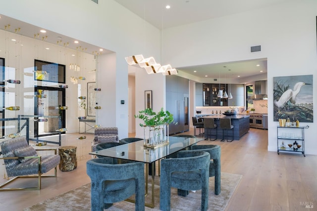 dining space with visible vents, a high ceiling, light wood-style floors, and recessed lighting