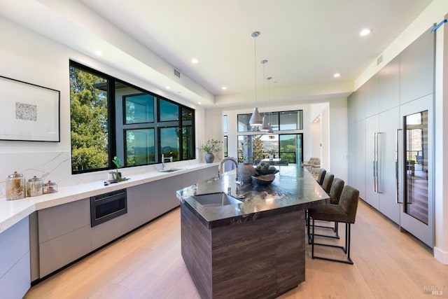 kitchen featuring a sink, modern cabinets, light wood-style floors, and gray cabinetry