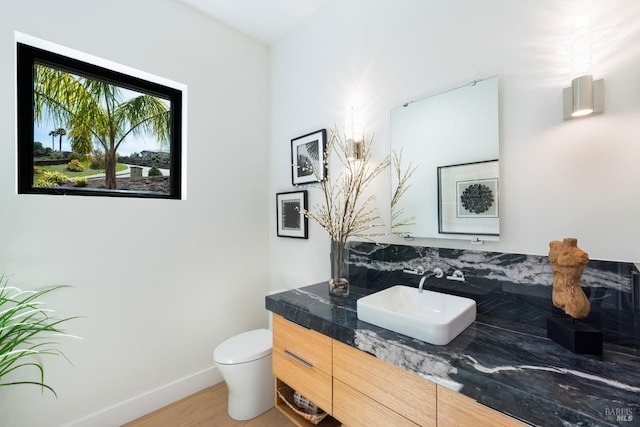 bathroom featuring baseboards, toilet, vanity, and wood finished floors