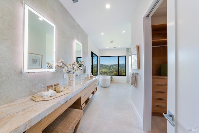 bathroom with a freestanding bath, vanity, baseboards, and recessed lighting
