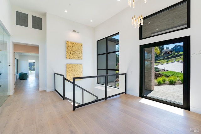 corridor featuring recessed lighting, a notable chandelier, baseboards, and wood finished floors