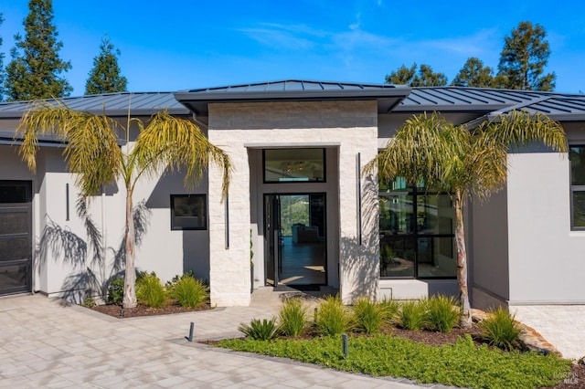 doorway to property featuring stucco siding, metal roof, a standing seam roof, and roof mounted solar panels