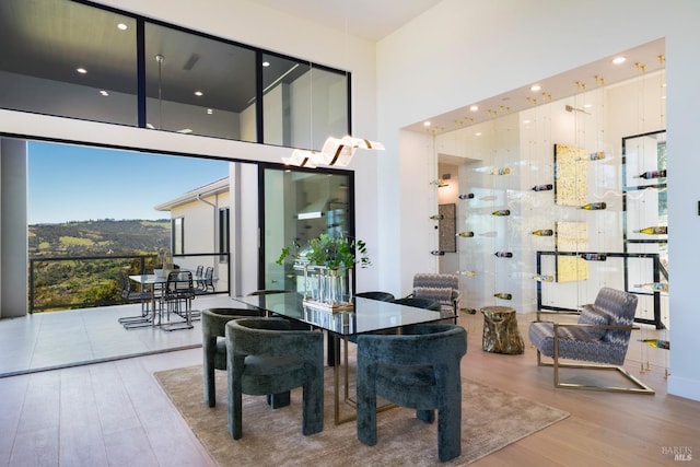 dining space with a towering ceiling and wood finished floors