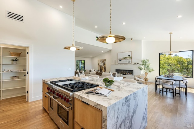559 E Spring St, Napa, CA 94559 - kitchen featuring range with two ovens, light wood finished floors, open floor plan, decorative light fixtures, and a glass covered fireplace