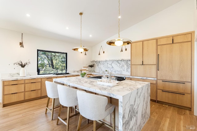 559 E Spring St, Napa, CA 94559 - kitchen with light brown cabinetry, decorative backsplash, an island with sink, light wood finished floors, and vaulted ceiling