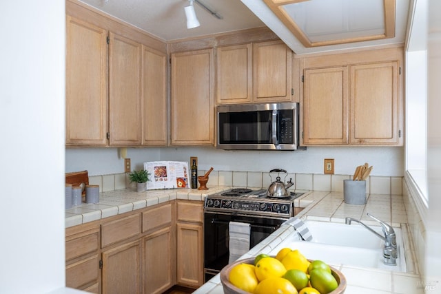 kitchen featuring tile countertops, black electric range oven, a sink, and stainless steel microwave