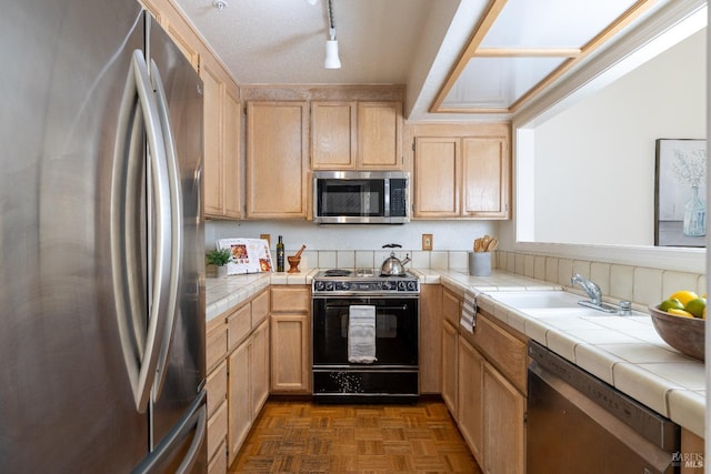 kitchen featuring light brown cabinets, tile countertops, a sink, and appliances with stainless steel finishes
