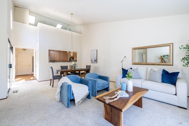 living room featuring light carpet, visible vents, a towering ceiling, and a chandelier