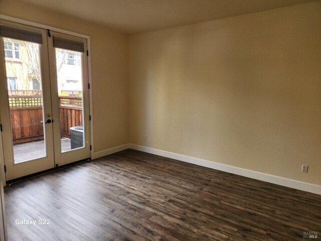 spare room with baseboards and dark wood-style floors