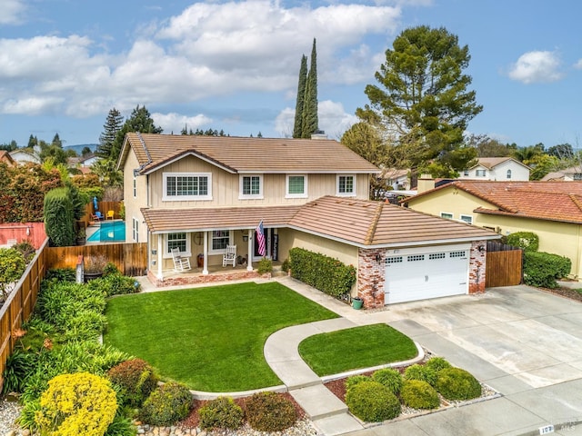 traditional-style home featuring a front yard, a tile roof, fence private yard, and a garage
