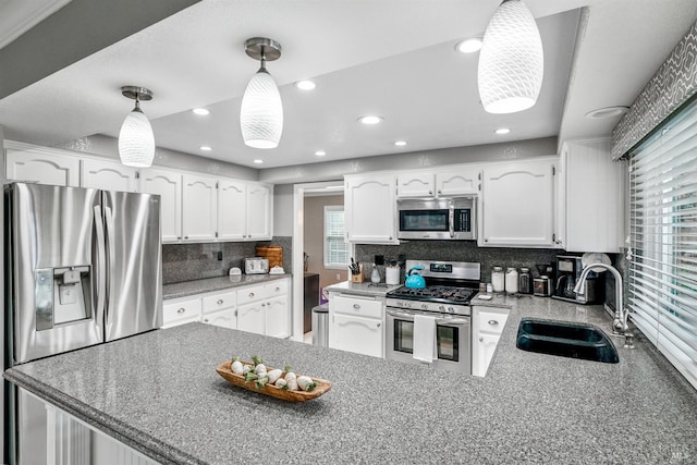 kitchen with white cabinetry, a sink, appliances with stainless steel finishes, and a wealth of natural light