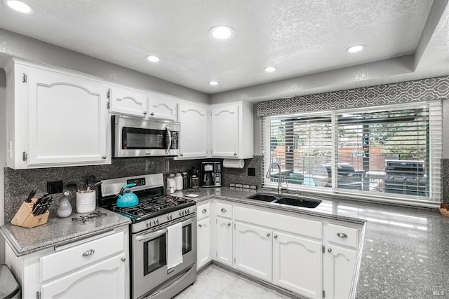 kitchen featuring a sink, white cabinetry, tasteful backsplash, appliances with stainless steel finishes, and a textured ceiling