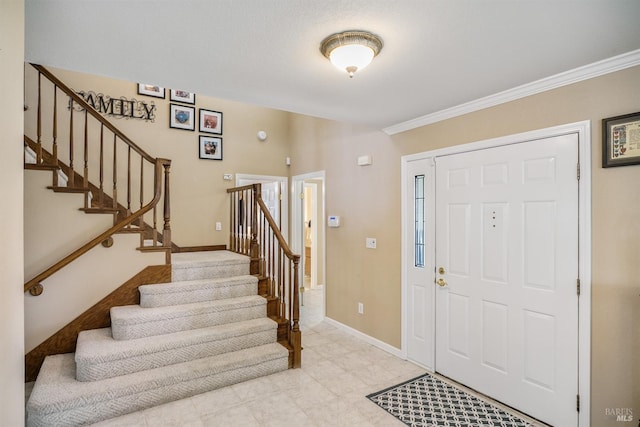 entrance foyer featuring baseboards, crown molding, and stairway