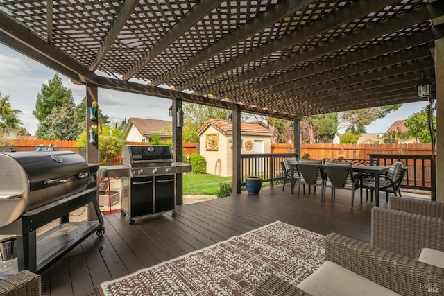 deck with a fenced backyard, outdoor dining space, area for grilling, and an outdoor structure