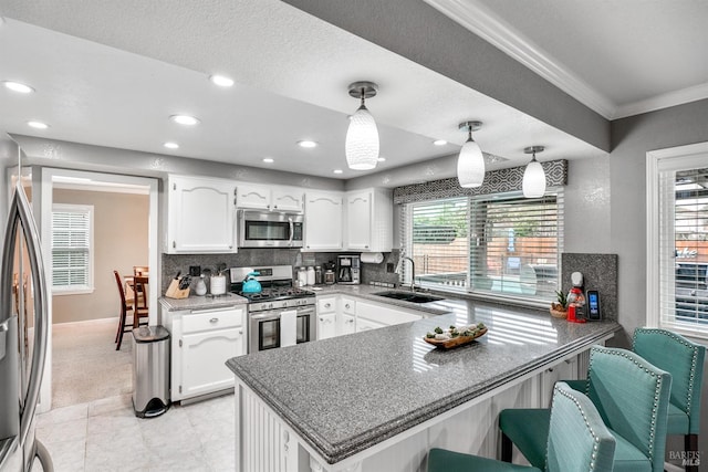 kitchen featuring tasteful backsplash, stainless steel appliances, a sink, white cabinets, and a peninsula
