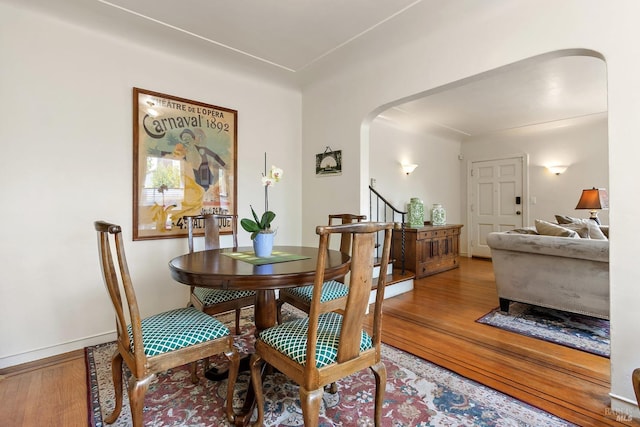 dining space with stairway, arched walkways, and wood finished floors