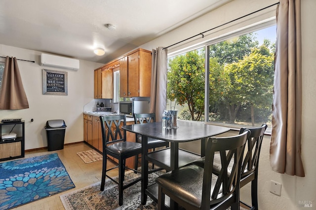 dining space featuring light wood finished floors, baseboards, and an AC wall unit