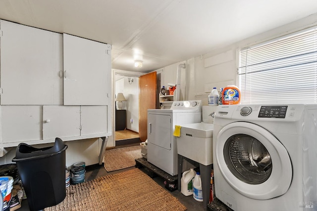 clothes washing area featuring separate washer and dryer and cabinet space