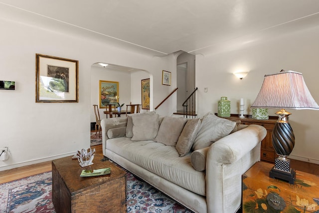 living area with arched walkways, baseboards, and wood finished floors