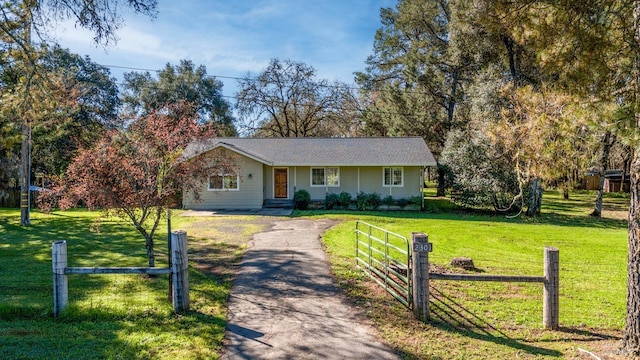 ranch-style home featuring a front lawn, fence, and aphalt driveway