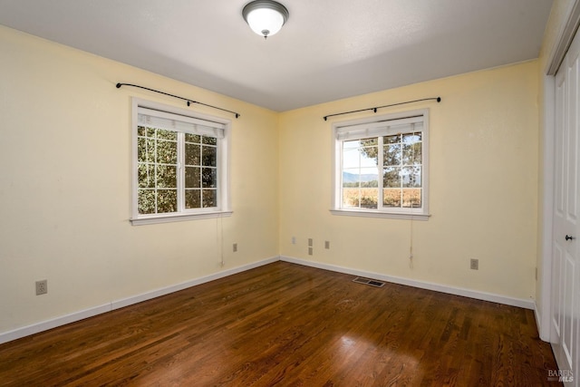 unfurnished bedroom featuring a closet, baseboards, dark wood finished floors, and visible vents