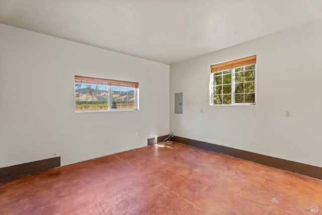 spare room featuring finished concrete floors and electric panel