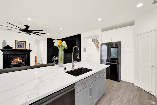 kitchen featuring a sink, smart refrigerator, light stone counters, and recessed lighting