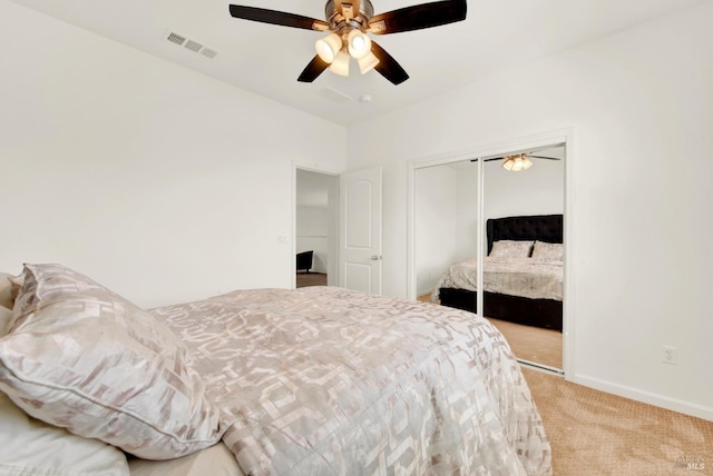 bedroom featuring a closet, baseboards, light colored carpet, visible vents, and ceiling fan