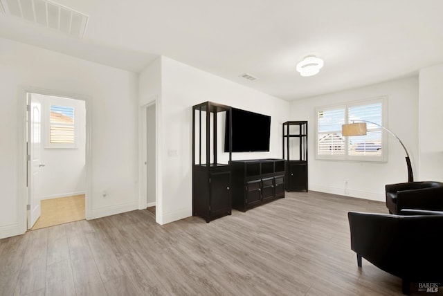 living area featuring baseboards, visible vents, and wood finished floors