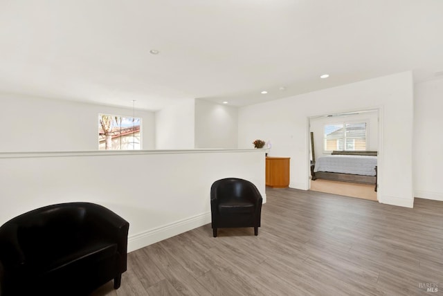 living area with light wood-style flooring, baseboards, and a healthy amount of sunlight