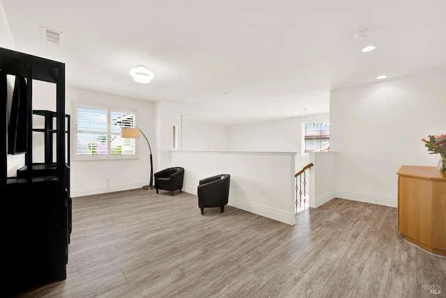 living area featuring an upstairs landing, recessed lighting, baseboards, visible vents, and light wood-style flooring