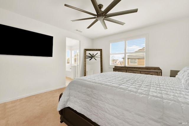 bedroom with visible vents, baseboards, ceiling fan, ensuite bath, and light colored carpet
