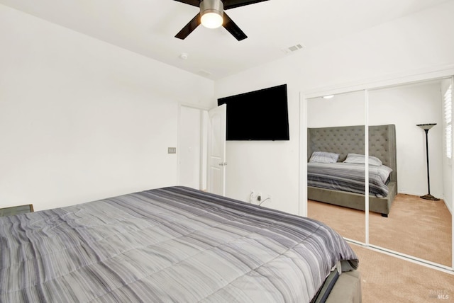 carpeted bedroom featuring visible vents, a closet, and a ceiling fan