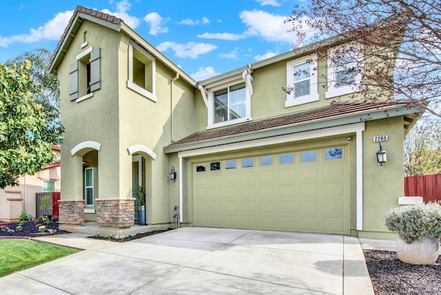 view of front of home with stucco siding, a garage, fence, and concrete driveway