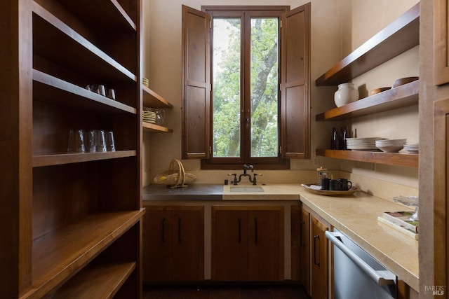 kitchen featuring dishwasher, light countertops, a sink, and open shelves