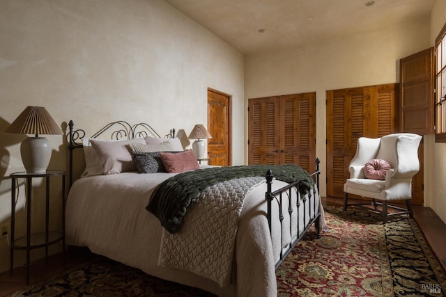 bedroom with two closets, a high ceiling, and wood finished floors