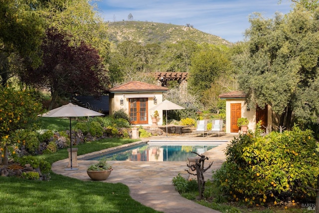 outdoor pool featuring an outdoor structure, french doors, an exterior structure, a yard, and a patio area