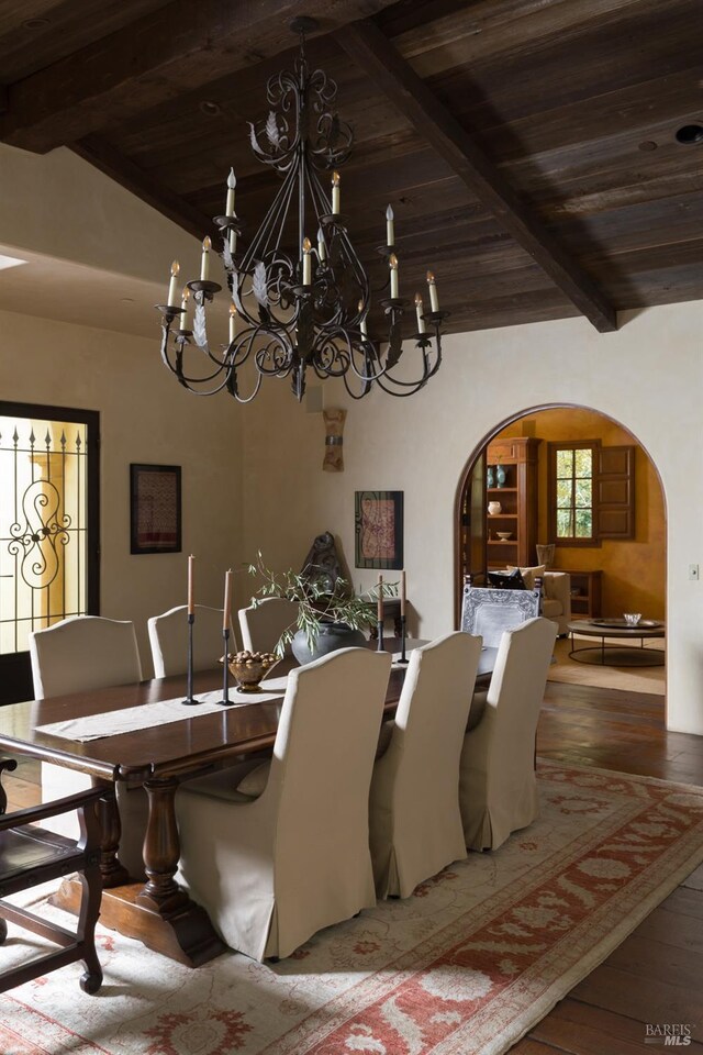 dining space featuring arched walkways, wooden ceiling, a notable chandelier, and beam ceiling