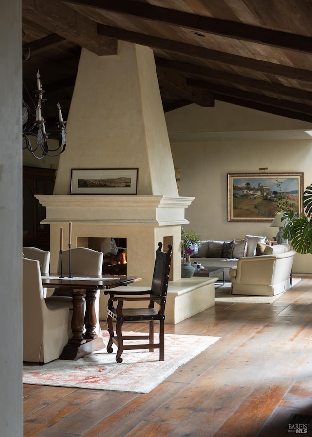 dining area featuring vaulted ceiling with beams, a high end fireplace, an inviting chandelier, and wood-type flooring