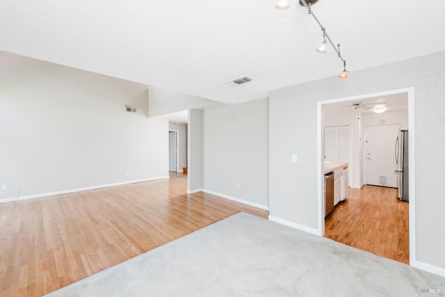 empty room featuring light wood-style floors, ceiling fan, baseboards, and visible vents
