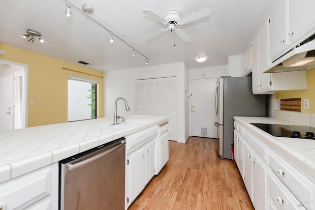kitchen featuring a sink, tile counters, appliances with stainless steel finishes, and under cabinet range hood