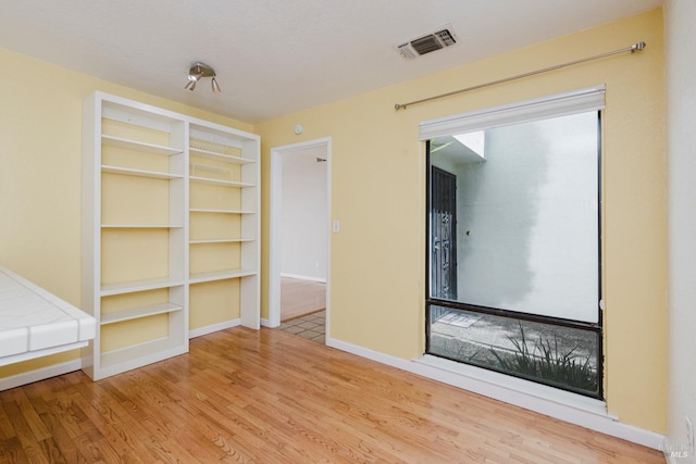 interior space with baseboards, wood finished floors, and visible vents