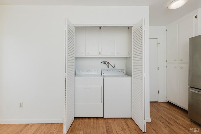 washroom featuring cabinet space, washer and clothes dryer, light wood finished floors, and baseboards