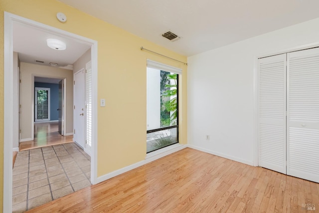 unfurnished bedroom with visible vents, baseboards, a closet, and light wood-style floors