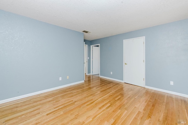 empty room featuring visible vents, baseboards, and wood finished floors