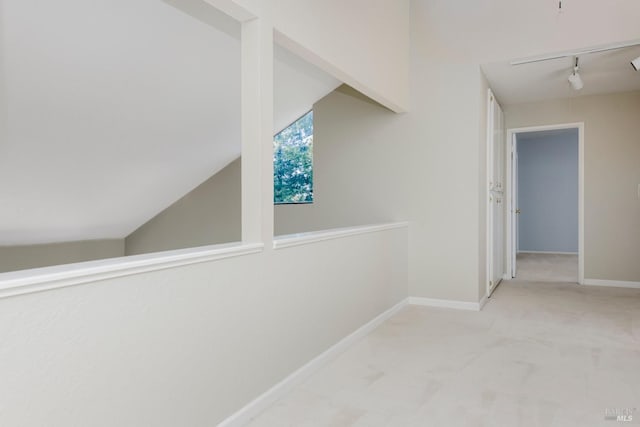 hallway with rail lighting, baseboards, and carpet floors