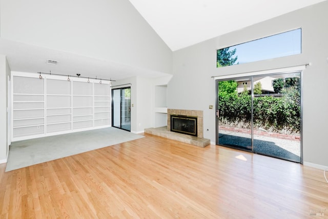 unfurnished living room featuring baseboards, built in features, a fireplace, high vaulted ceiling, and wood finished floors