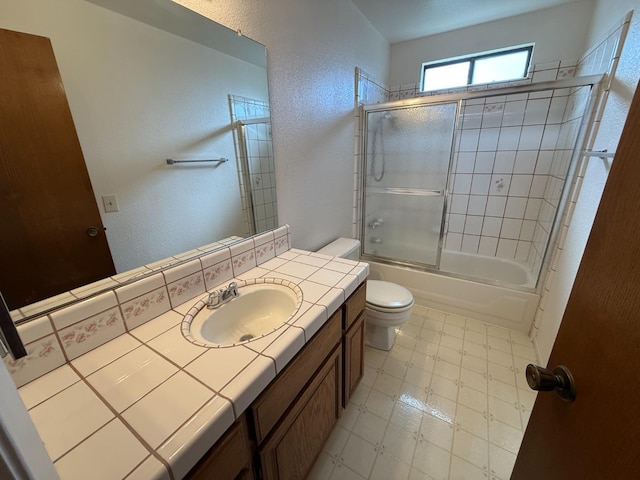 full bathroom with a textured wall, vanity, toilet, tile patterned floors, and enclosed tub / shower combo