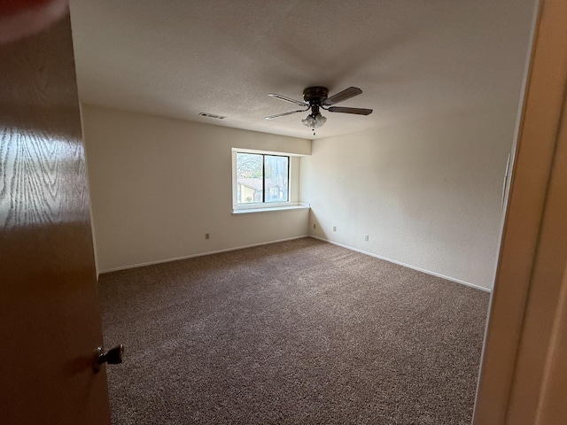 carpeted spare room featuring ceiling fan, visible vents, and baseboards